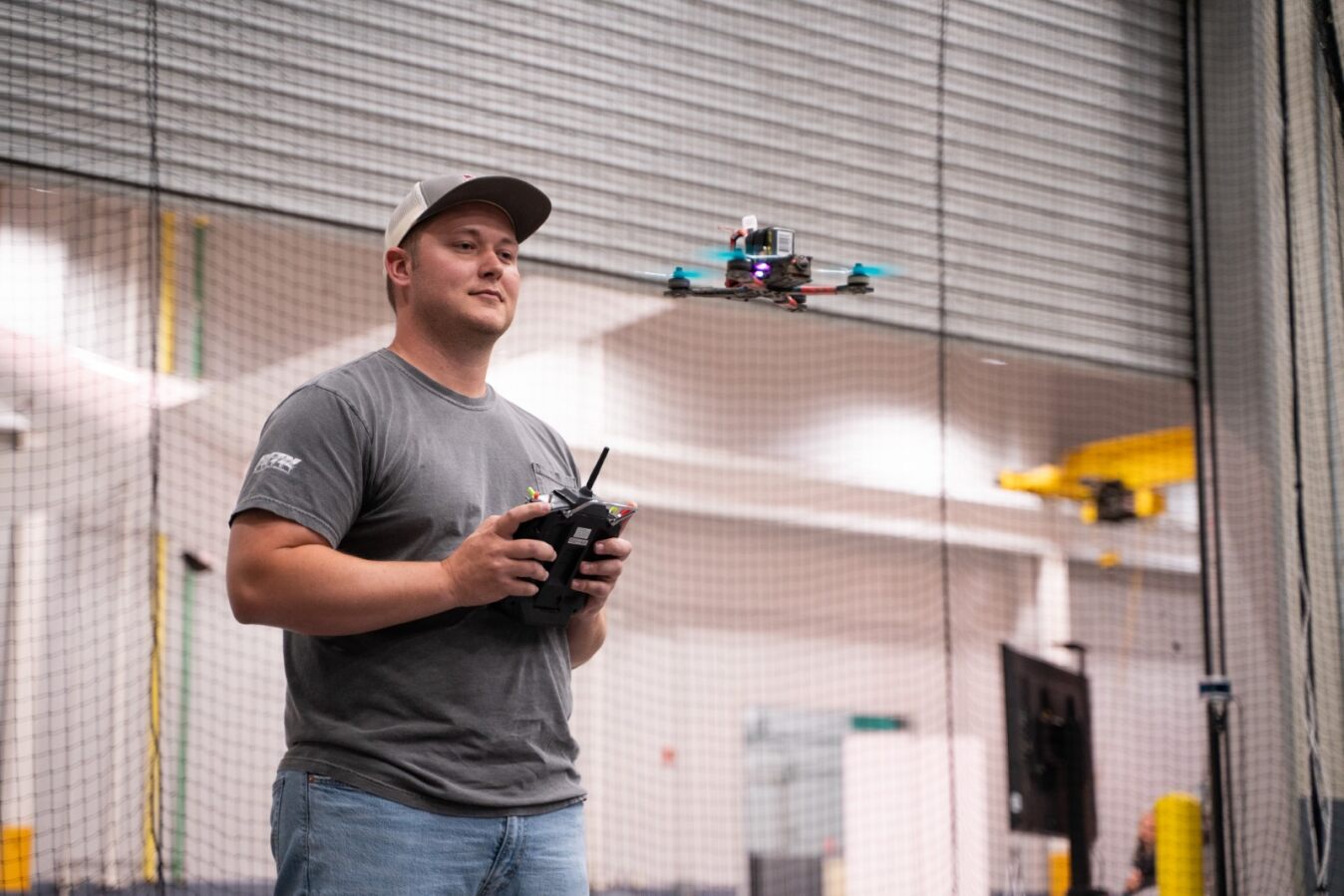 Man holding a controller that is moving a small drone